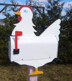 a white chicken mailbox sitting in the grass