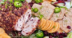 a platter filled with crackers, vegetables and meat