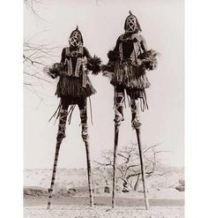 two native american people standing next to each other in front of a tree with no leaves