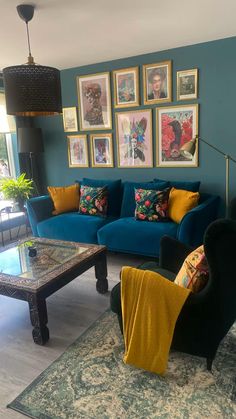 a living room filled with blue couches and pictures on the wall above them,