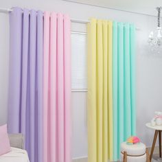 the curtains are colored in different colors and sizes, along with a white chair next to it