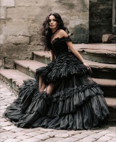 a woman in a black dress sitting on some steps