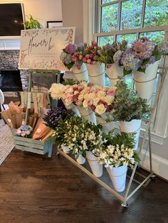 flowers are arranged in white pots on a table near a sign that says flower shop