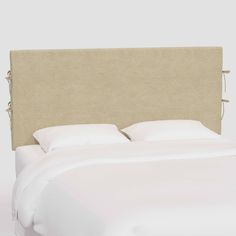 an upholstered headboard with white sheets and pillows