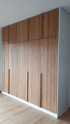 an empty room with wooden cupboards and hard wood flooring on the side wall