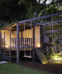 a small wooden structure with swings and lights on the roof is lit up at night