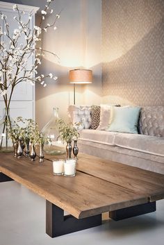 a living room with a couch, table and flowers in vases on the coffee table