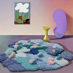 a rug with flowers on it next to a vase and painting in the background,