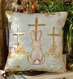 a decorative pillow with an image of a bunny and cross on the front is shown