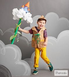 a young boy is holding a flower in front of a cloud backdrop with a house on it