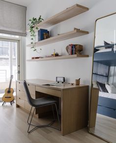 a bedroom with a desk, mirror and guitar