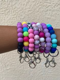 a woman's arm with several bracelets and charms on it, all in different colors