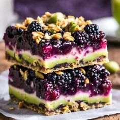 three dessert bars stacked on top of each other with blueberries, raspberries and almonds