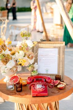 a red phone sitting on top of a table next to a vase filled with flowers