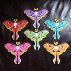 six cross stitched butterflies sitting on top of a black leather couch