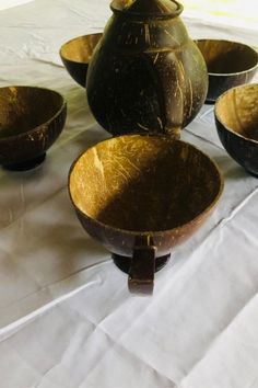 a table topped with lots of bowls and vases on top of a white cloth