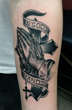 a black and white tattoo with an image of two hands holding a cross, in god's hands