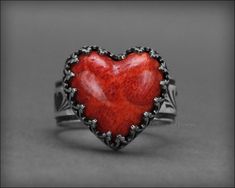 This gorgeous Red Coral Heart Ring is sure to make a statement with that bold red color. A perfect gift for your sweetheart. The heart is made of a red coral composite, which consists of coral cuttings and pigmented resin from the coral cuttings. It sits in a sterling gallery bezel setting, with an inverted heart design. The ring shank is a sterling silver wide band with a heart pattern. The ring has been oxidized to bring out all the lovely details. 𝙏𝙝𝙞𝙨 𝙙𝙚𝙨𝙞𝙜𝙣 𝙞𝙨 𝙤𝙧𝙞𝙜𝙞𝙣𝙖𝙡 ? Valentine's Day Red Heart Sterling Silver Ring, Red Heart-shaped Sterling Silver Rings, Red Sterling Silver Heart-shaped Rings, Heart-shaped Red Sterling Silver Rings, Red Sterling Silver Heart Ring As Gift, Unique Red Heart Shaped Jewelry, Handmade Red Heart-shaped Rings, Unique Heart Ring For Valentine's Day, Handmade Red Rings For Valentine's Day