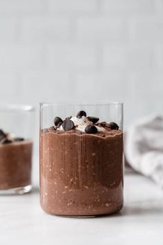 two glasses filled with chocolate pudding on top of a white counter next to each other