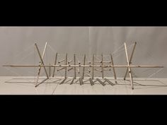 an artistic sculpture made out of sticks and wires on a white surface with grey background