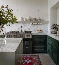 a kitchen with marble counter tops and green cabinets, along with a rug on the floor