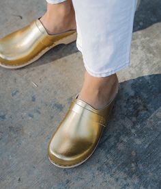 "Step into the radiance of the holiday season with our timeless Metallic Gold Leather Tokyo Clog Mules. Meticulously crafted for both quality and comfort, these low-heeled classics boast a captivating Metallic Gold hue that gleams like festive treasures. The light wooden base complements the lustrous leather, creating an elegant silhouette that effortlessly captures the essence of refined style. Step confidently into the spotlight with our Tokyo Metallic Gold Clog Mules - a fusion of timeless el Sandgrens Clogs, Clog Mules, Mules Women, Clogs For Women, Swedish Clogs, Leather Clog, Clogs And Mules, Clog Boots, Clogs Style