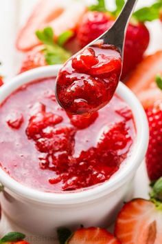 a spoon full of strawberry jam on top of strawberries