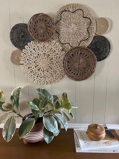 a wooden table topped with a potted plant next to a wall mounted wicker art piece