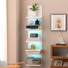 a white shelf filled with books and electronic gadgets next to a wall mounted clock