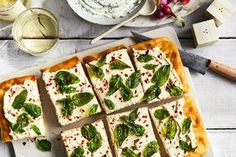 flat bread with cheese and spinach on a cutting board next to other food items