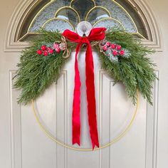 a wreath with red ribbon hanging on the front door