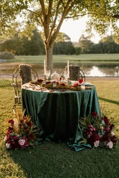 an outdoor table set up with flowers and plates on it for a formal dinner in the park