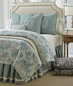 a bed with blue and white bedspread, pillows and pillowcases on top of it