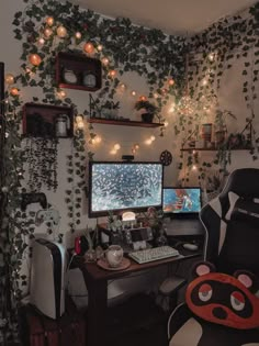 a computer desk topped with a monitor next to a wall covered in plants and lights