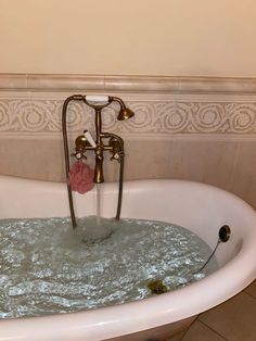 a bathtub filled with water next to a wall mounted faucet in a bathroom