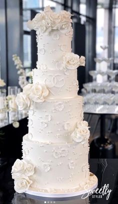 a wedding cake with white flowers on it is sitting on a table in the middle of a room