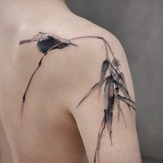 the back of a woman's shoulder with an inked bamboo plant on it