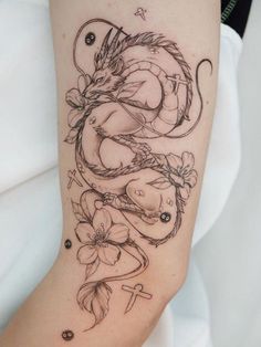 a woman's arm with a dragon and flowers tattoo design on the left forearm