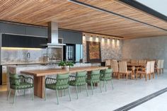 a dining room and kitchen area with wood ceilinging, green chairs and table in the middle