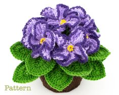 crocheted purple flowers in a pot with green leaves on the top and bottom