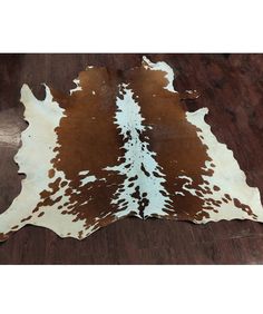 a brown and white cowhide rug on a wooden floor