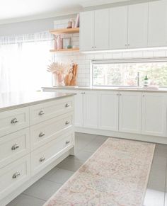 a kitchen with white cabinets and an area rug in front of the counter top on the floor