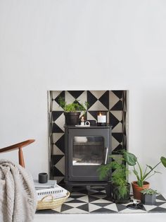 a living room with black and white tiles on the wall, potted plants and a fireplace