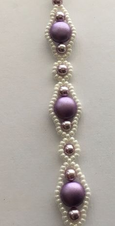 the beaded bracelet is purple and white with silver beads on each strand, along with pearls