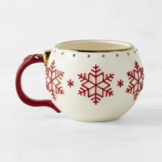 a red and white coffee cup with snowflakes on the inside is sitting on a table