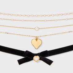 Five-piece choker necklace set from Wild Fable™ in gold tones. Includes one black fabric necklace embellished with a bow and heart charm plus four dainty chain necklaces featuring various designs. Chains include one adorned with a gold-finish heart, another with a white faux-pearl charm, and two embellished with white faux pearls interspersed among chain links. Four-inch extender chains help you find the perfect fit. If you’re not satisfied with any Target Owned Brand item, return it within one Gold Choker For Valentine's Day Party, Accesorios Aesthetic, Dainty Chain Necklace, Charm Choker Necklace, Trending Necklaces, Fabric Necklace, Choker Necklace Set, Initial Pendant Necklace, Dainty Chain