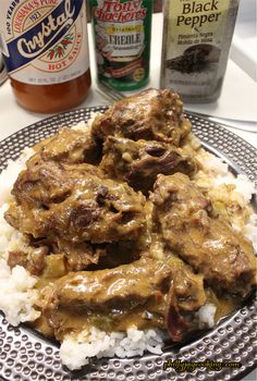 a plate with rice, meat and gravy next to two bottles of beer