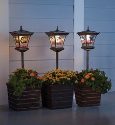 three planters with flowers in them on the side of a house