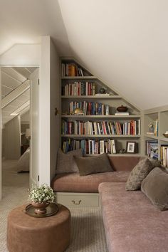 a living room filled with lots of books on top of a book shelf next to a couch