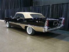 an old black and white car parked in front of a curtained wall with curtains behind it